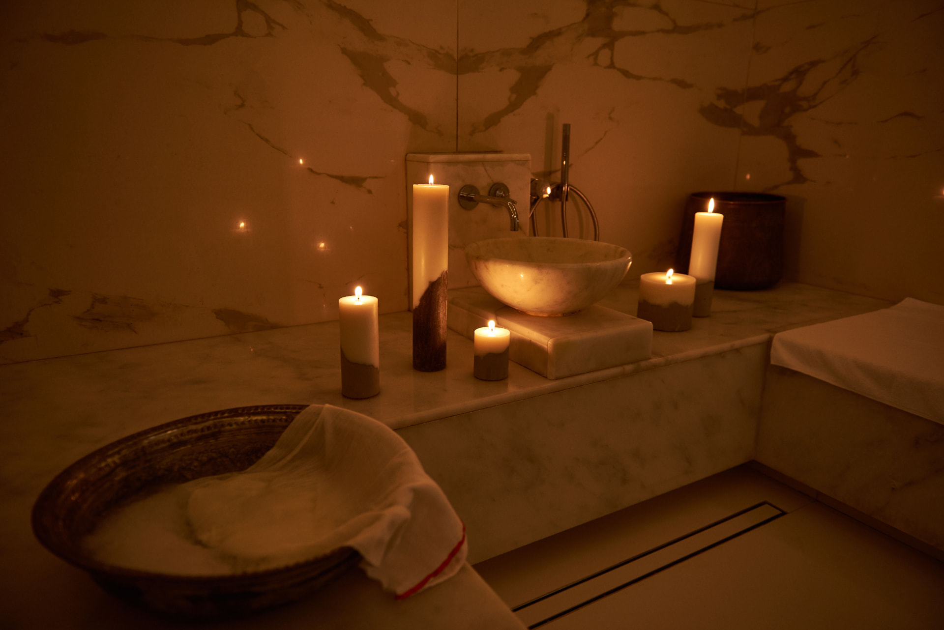 Marble basin and candles in a warm candle-lit hammam